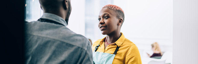Woman in apron talking with coworker