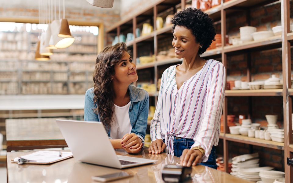 Two women working in warehouse with laptop